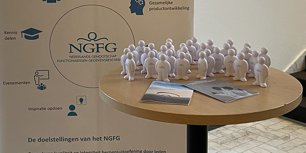 Beeld van banner NGFG en statafel met NGFG anti-stress-poppetjes Beeld van banner NGFG en statafel met NGFG anti-stress-poppetjes